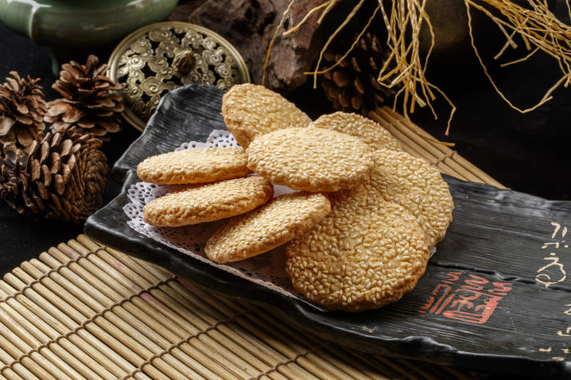 寿司帘上的黑磁盘装的芝麻烤饼图片