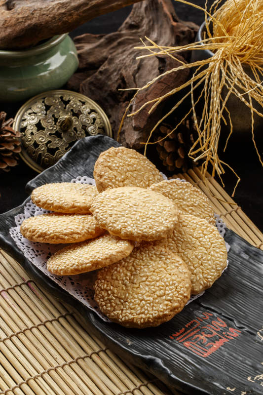 寿司帘上的黑磁盘装的芝麻烤饼图片
