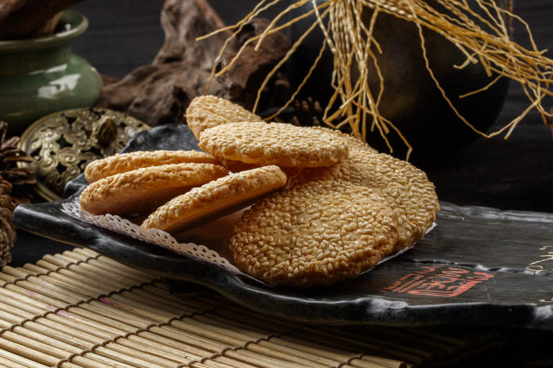 寿司帘上的黑磁盘装的芝麻烤饼图片
