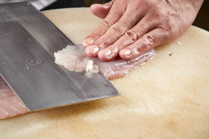 白色砧板上厨师用精湛的刀工展示生鱼片及鲜鱼料理切割分切的刀工图片