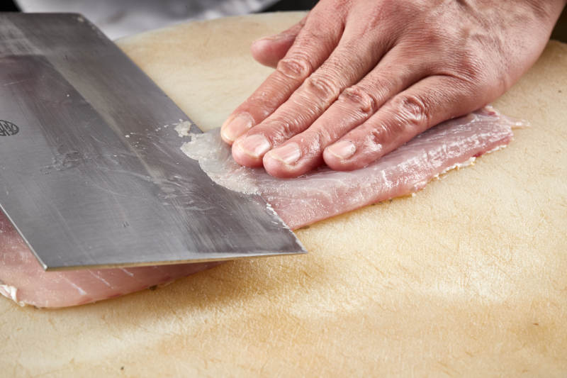 白色砧板上厨师用精湛的刀工展示生鱼片及鲜鱼料理切割分切的刀工图片