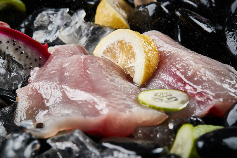 将晶莹白润的鲜鱼片码放在黑色的圆瓷盘上图片