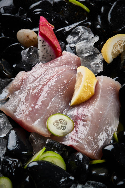 将晶莹白润的鲜鱼片码放在黑色的圆瓷盘上图片