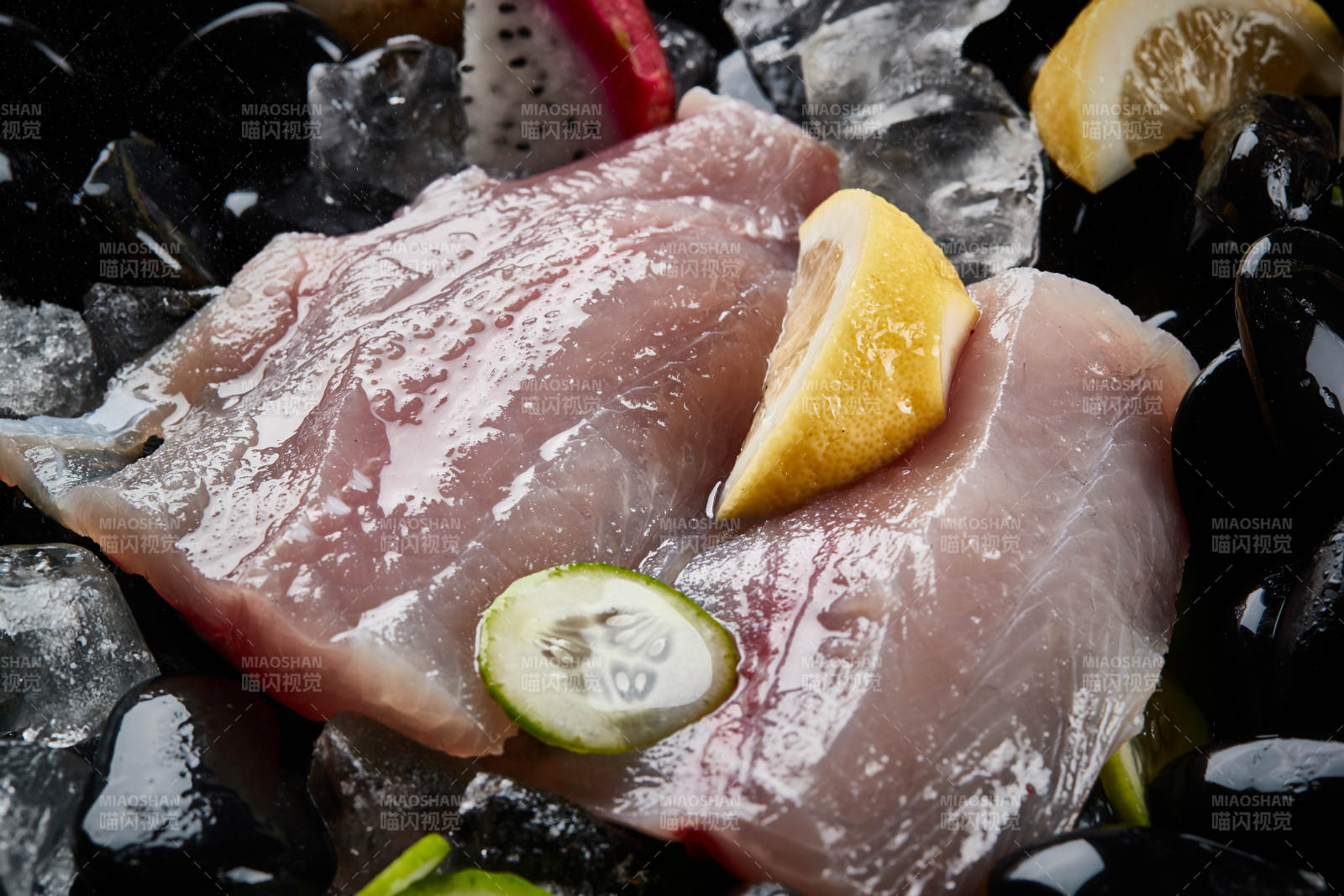 将晶莹白润的鲜鱼片码放在黑色的圆瓷盘上图片