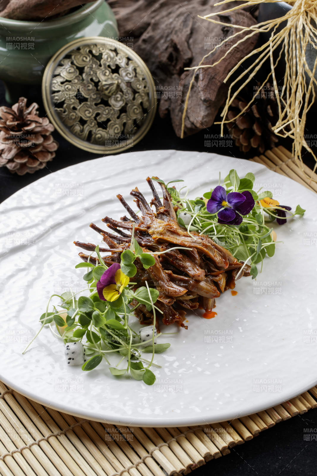 寿司帘上的圆瓷盘装的香辣鸭舌图片