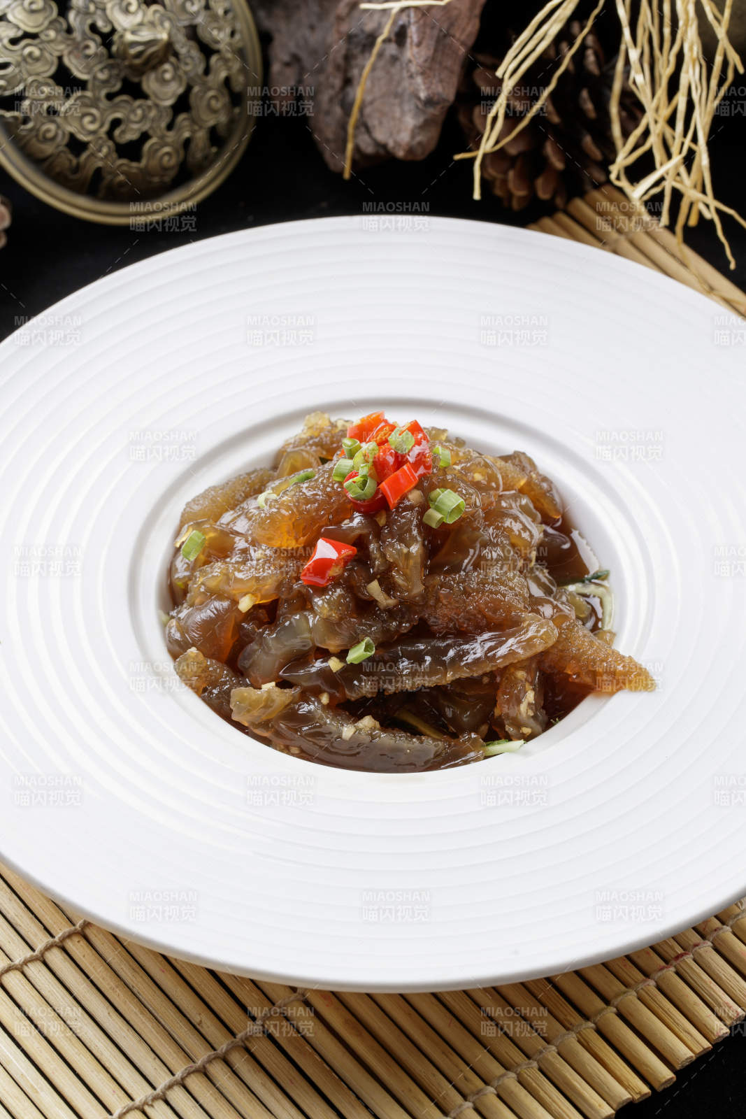 寿司帘上的圆瓷盘装的老醋蛰头图片