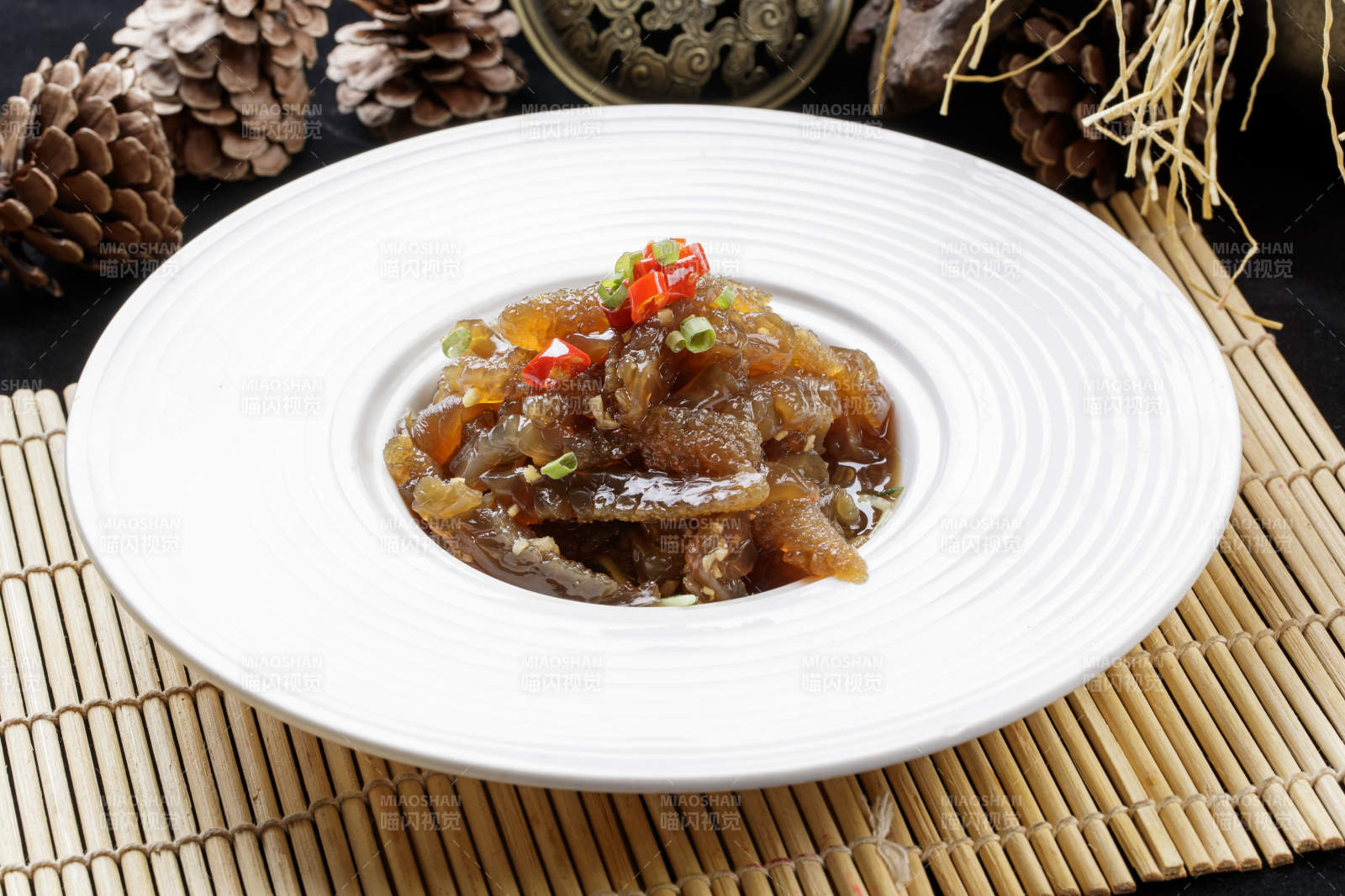 寿司帘上的圆瓷盘装的老醋蛰头图片