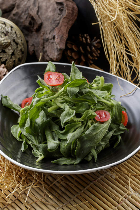 寿司帘上的圆瓷盘装的凉拌穿心莲图片