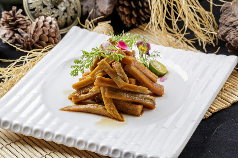 寿司帘上的方瓷盘装的暴腌萝卜条图片