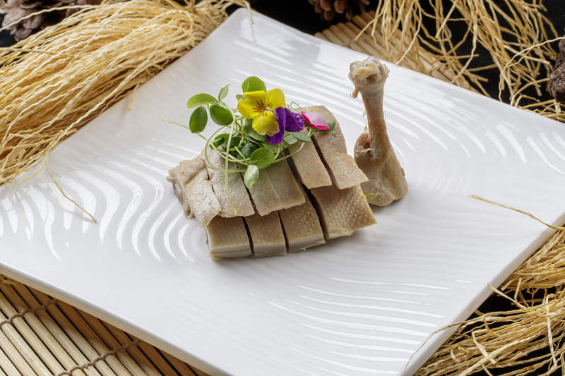 寿司帘上的方瓷盘装的盐水鸡腿图片