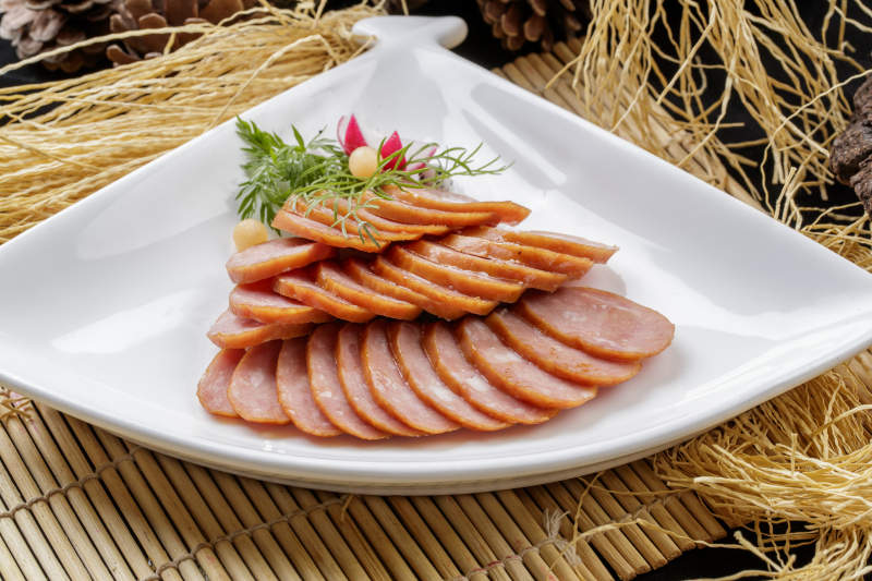 寿司帘上的扇形瓷盘装的自制蒜味香肠图片