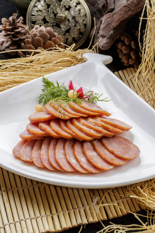 寿司帘上的扇形瓷盘装的自制蒜味香肠图片