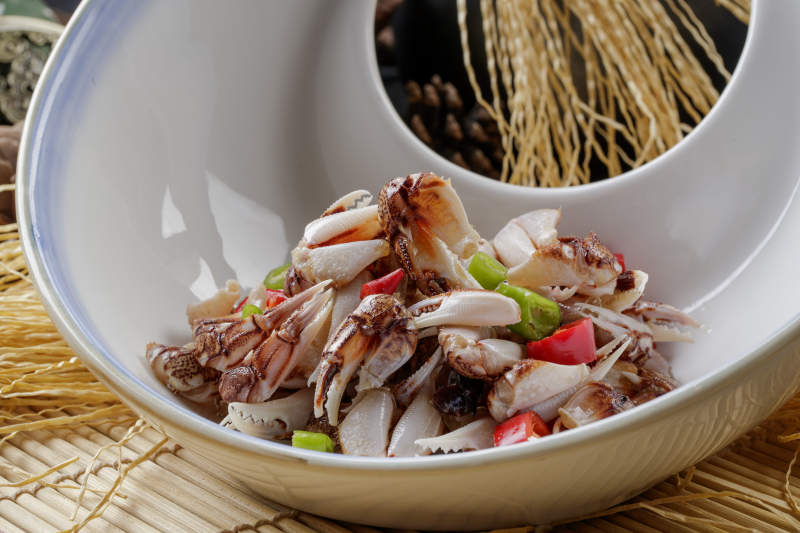 寿司帘上的异形瓷盘装的糟醉蟹钳图片