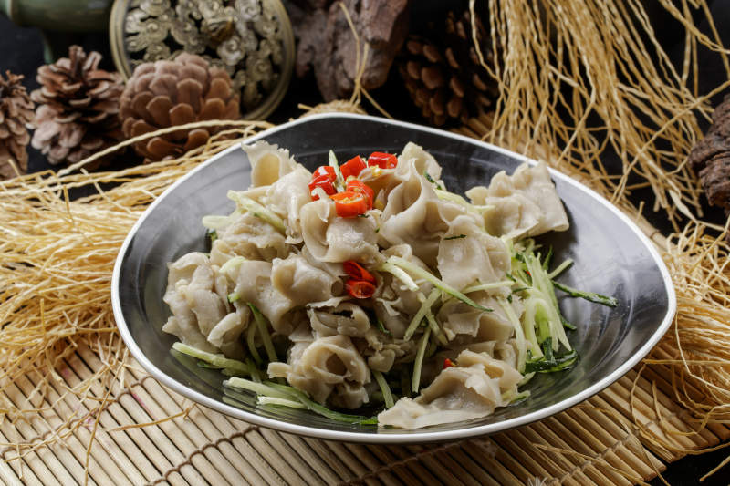 寿司帘上的黑瓷碗装的一品凉拌莜面窝窝图片