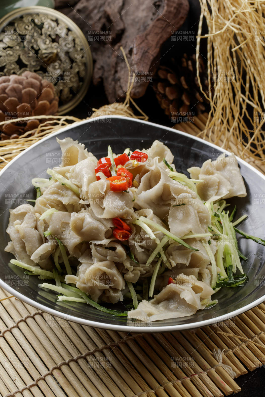 寿司帘上的黑瓷碗装的一品凉拌莜面窝窝图片