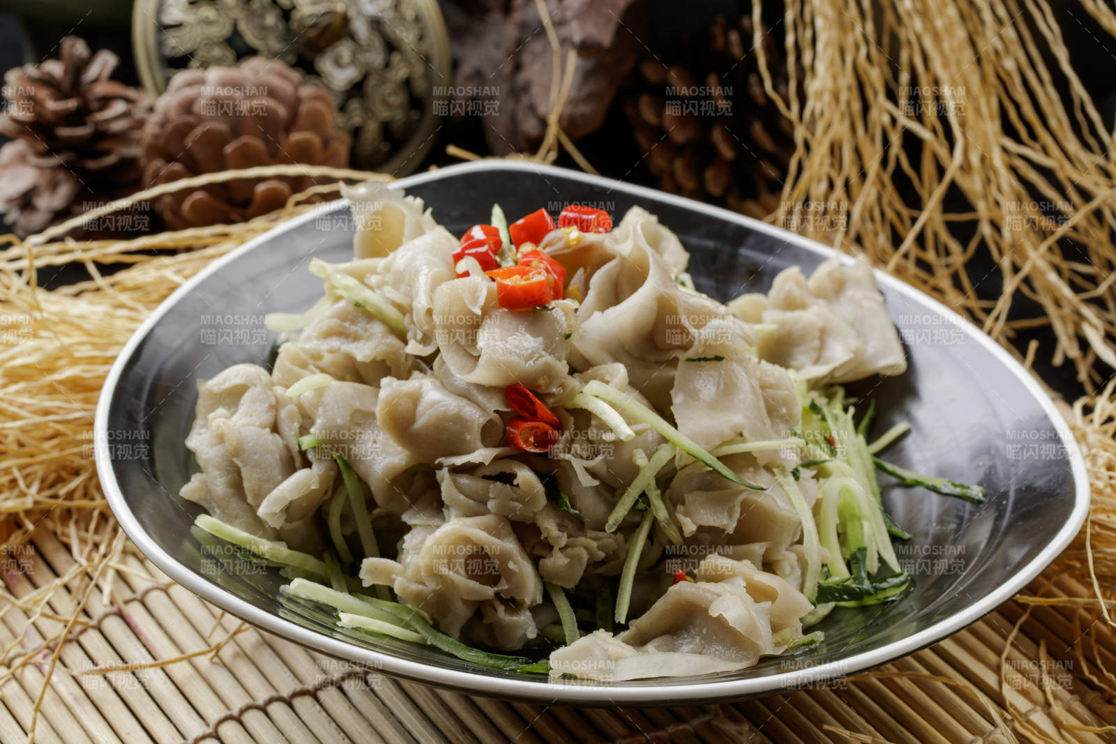 寿司帘上的黑瓷碗装的一品凉拌莜面窝窝图片