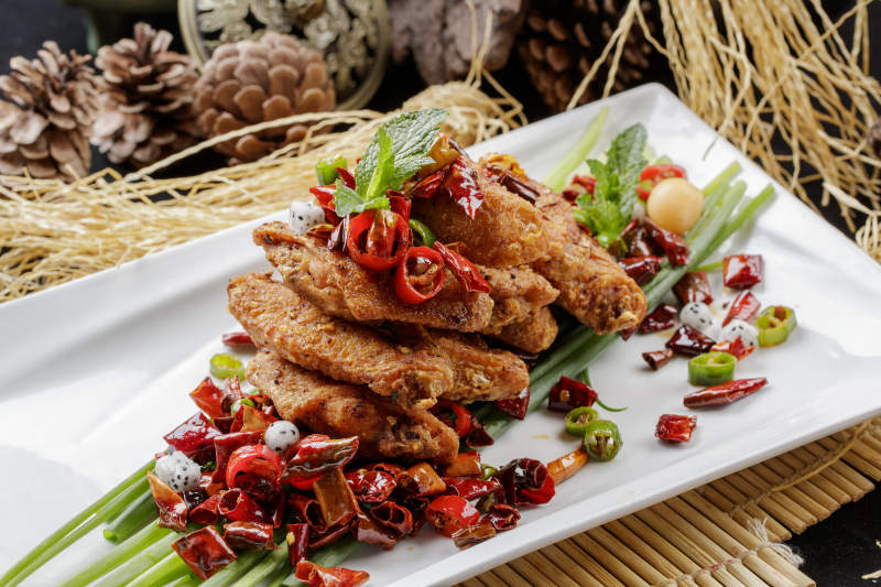 白色瓷盘装的香辣干炸鸡翅中图片