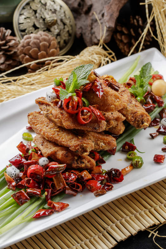 白色瓷盘装的香辣干炸鸡翅中图片