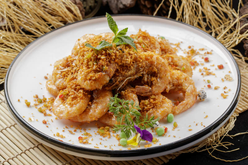 寿司帘上的圆瓷盘装的酥炸大明虾图片