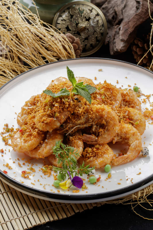 寿司帘上的圆瓷盘装的酥炸大明虾图片