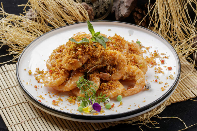 寿司帘上的圆瓷盘装的酥炸大明虾图片