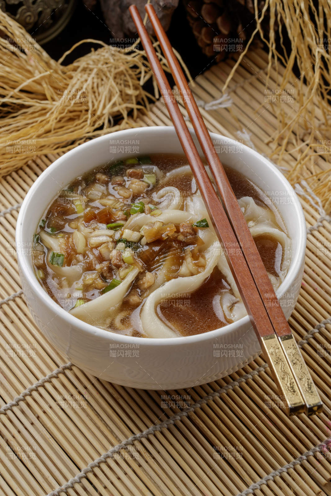 寿司帘上的白瓷碗装的茄丁打卤面图片