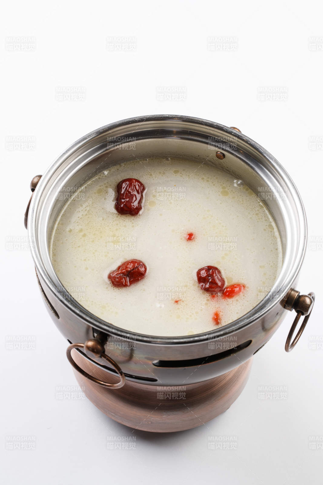 白色背景上的小火锅装的大骨奶汤锅底图片