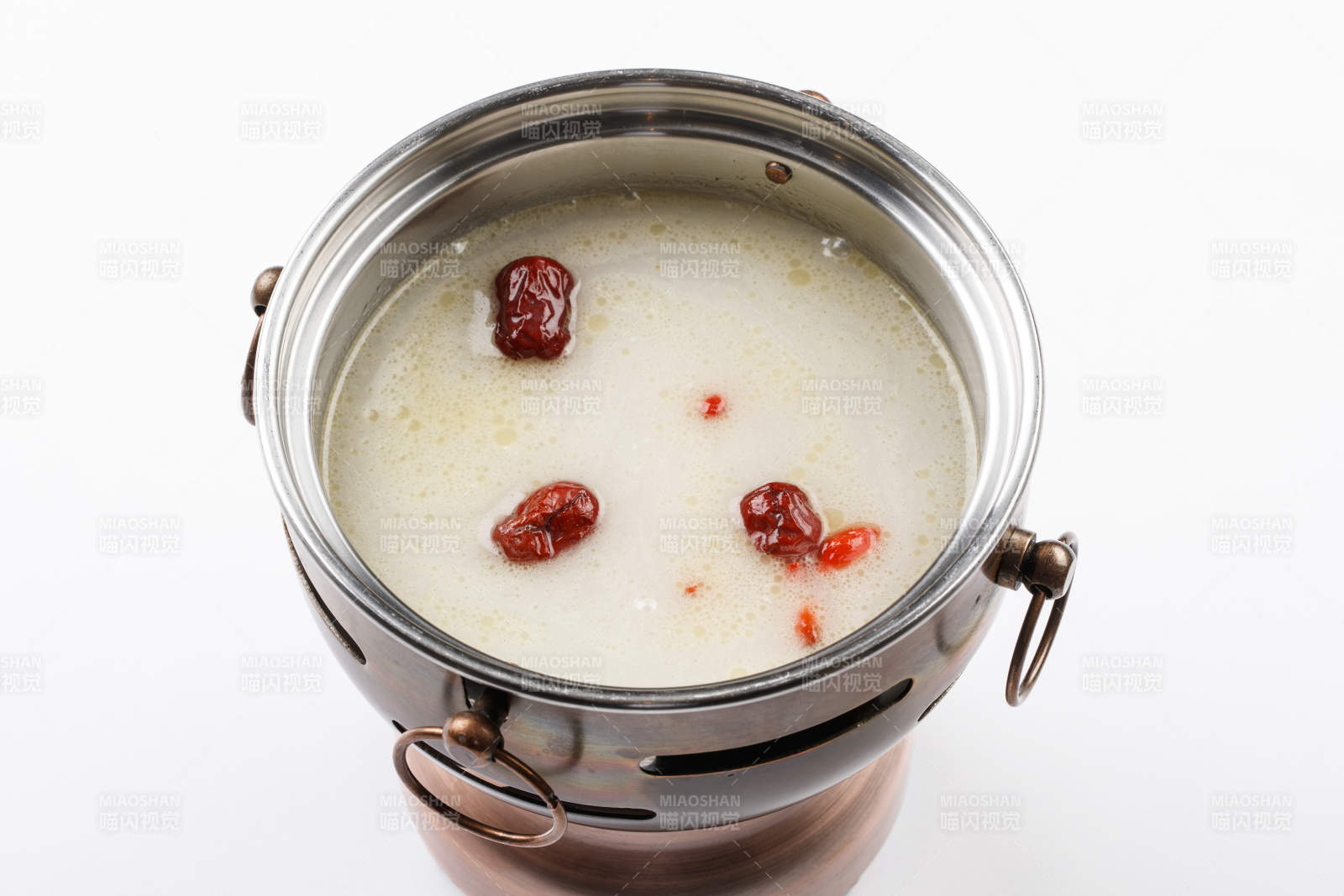 白色背景上的小火锅装的大骨奶汤锅底图片