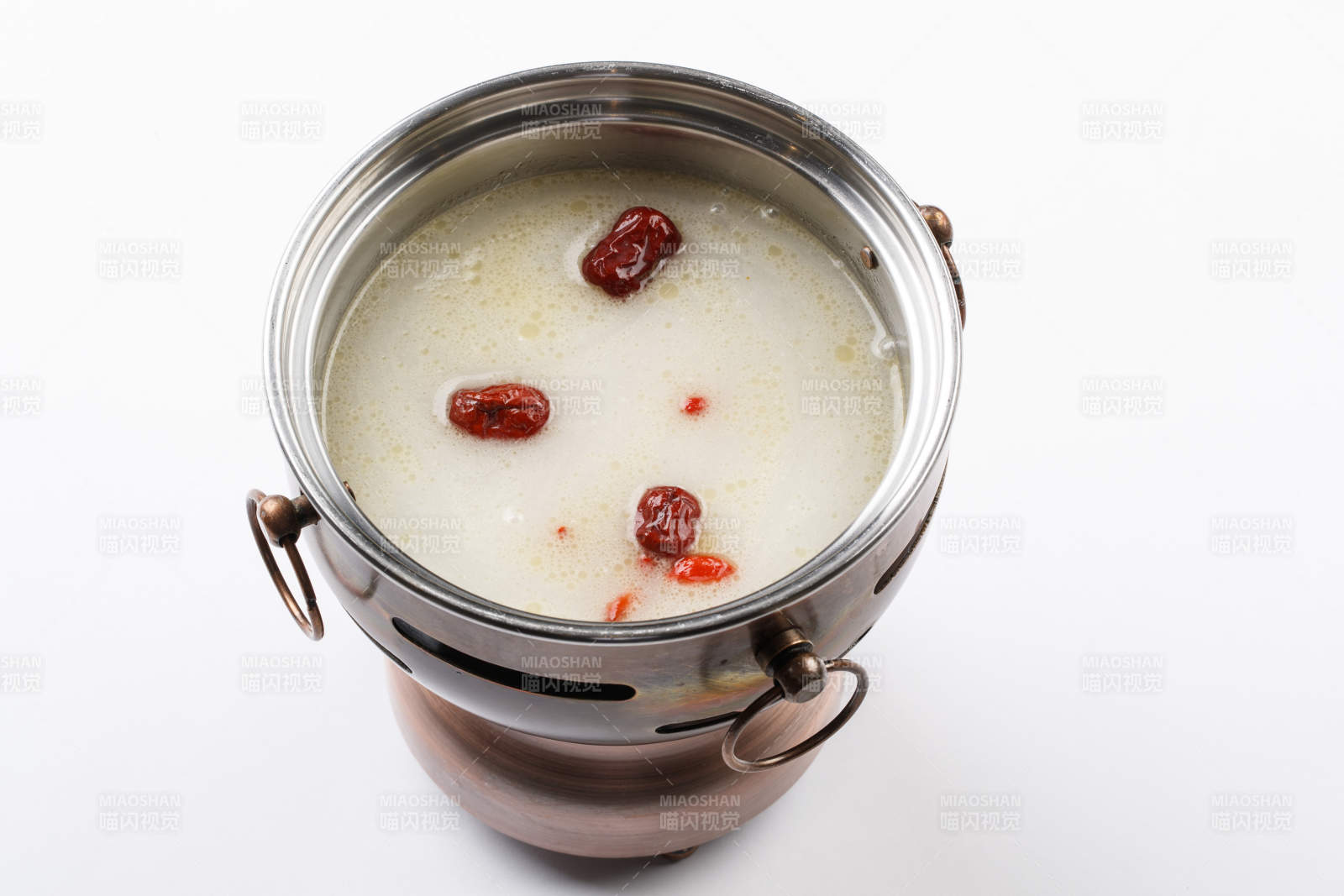 白色背景上的小火锅装的大骨奶汤锅底图片