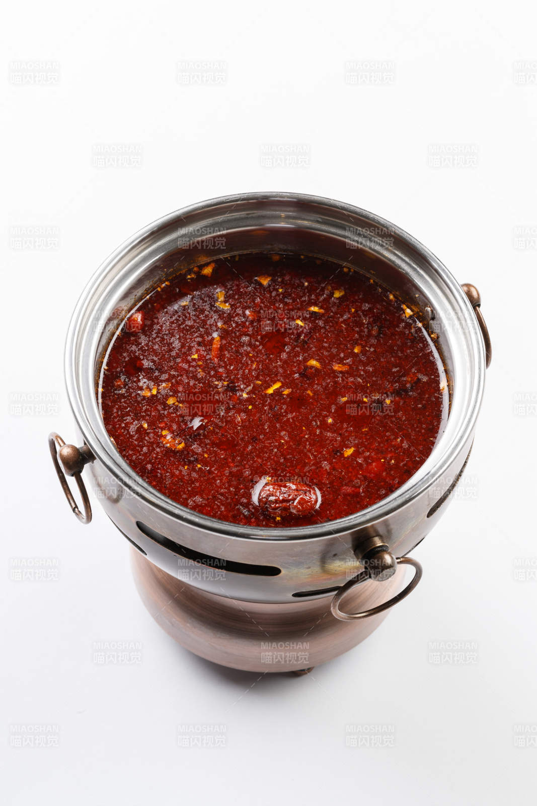 白色背景上的小火锅装的红油麻辣锅底图片