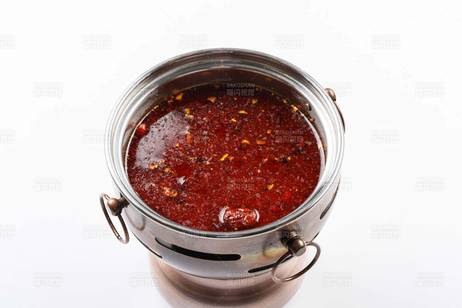 白色背景上的小火锅装的红油麻辣锅底图片