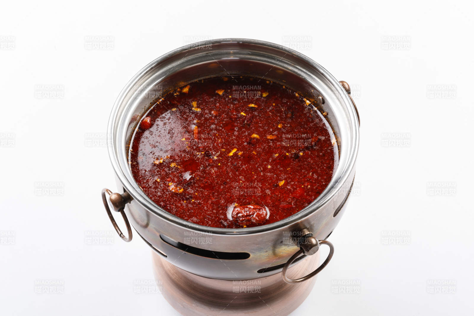 白色背景上的小火锅装的红油麻辣锅底图片