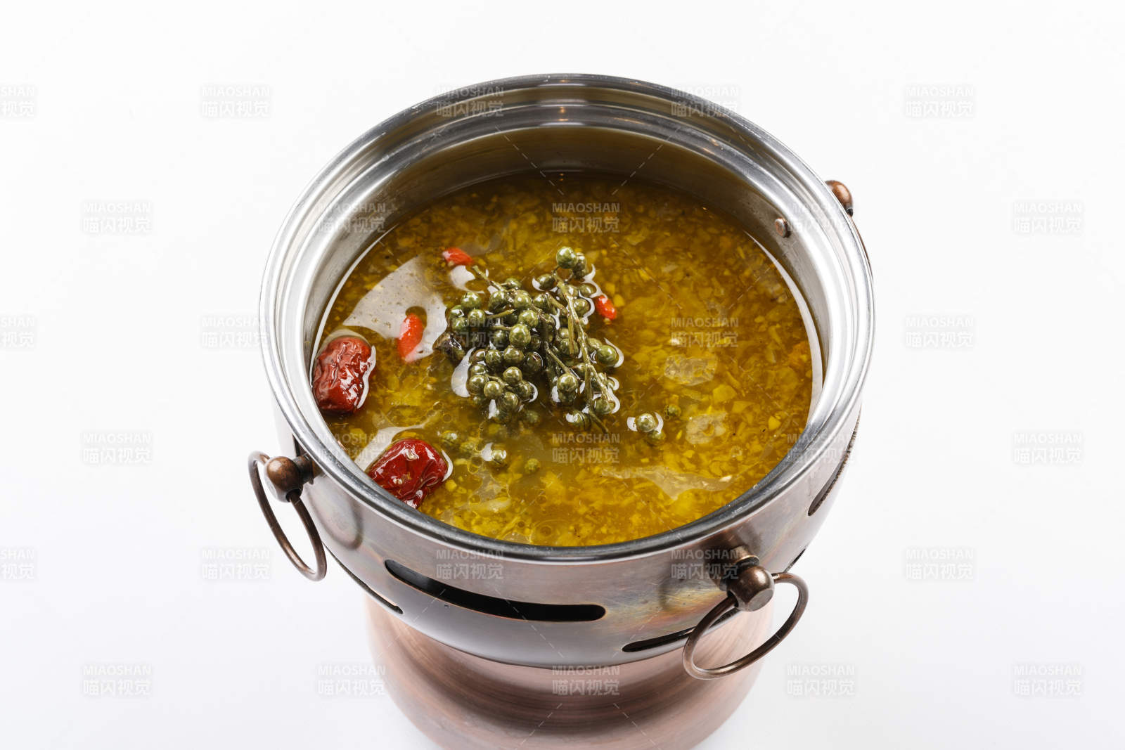 白色背景上的小火锅装的牛油藤椒酸辣锅底图片