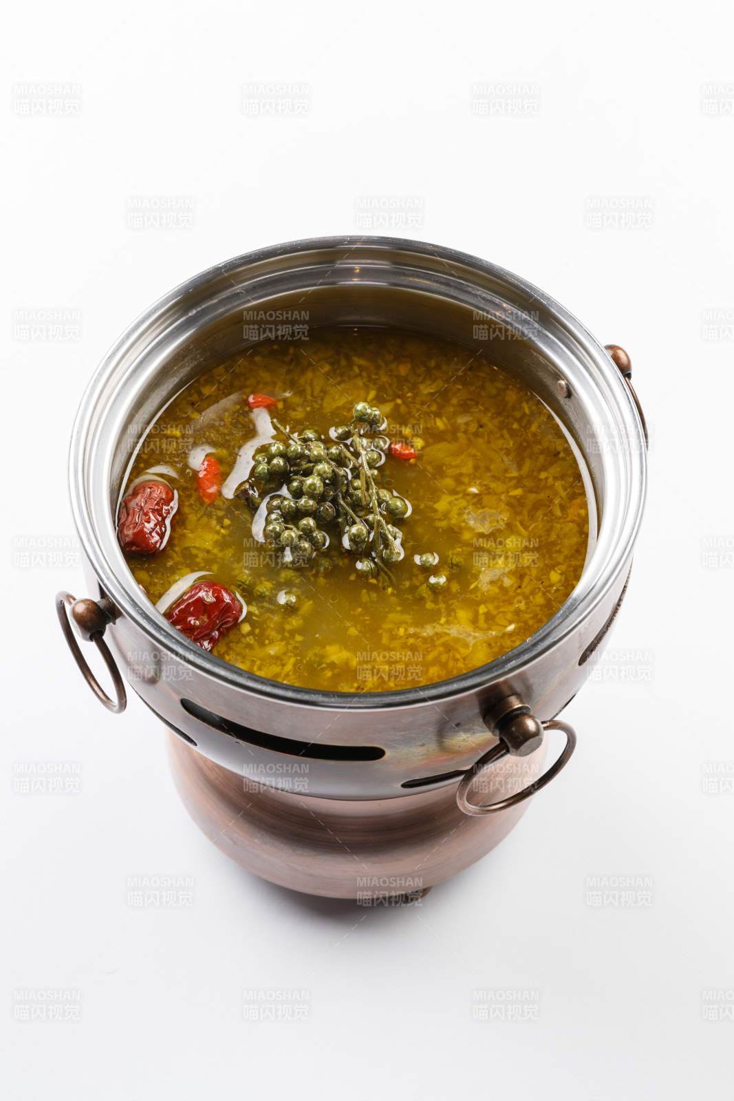白色背景上的小火锅装的牛油藤椒酸辣锅底图片