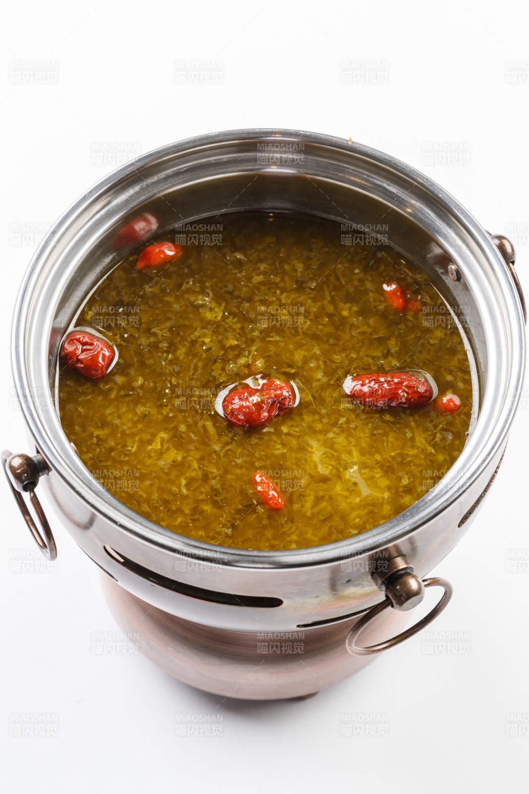 白色背景上的小火锅装的雪菜牛油锅底图片