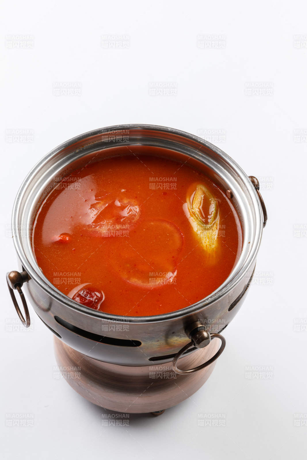 白色背景上的小火锅装的番茄锅底图片