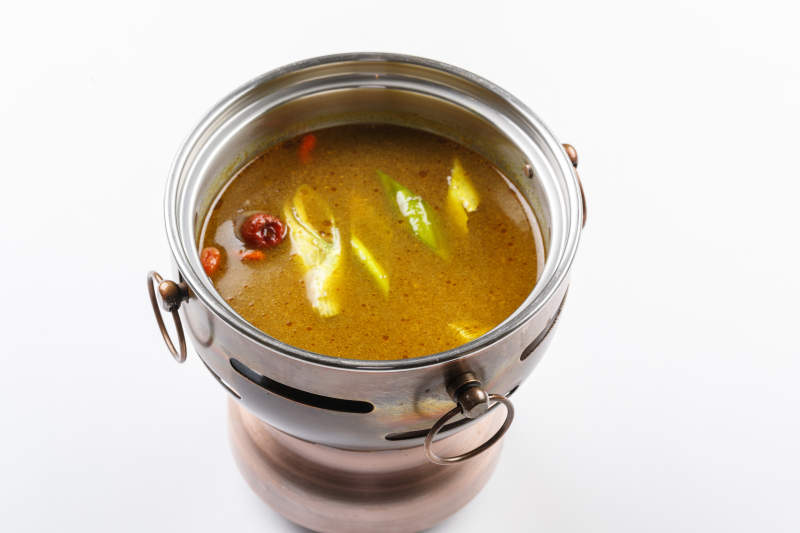 白色背景上的小火锅装的鸡汤锅底图片