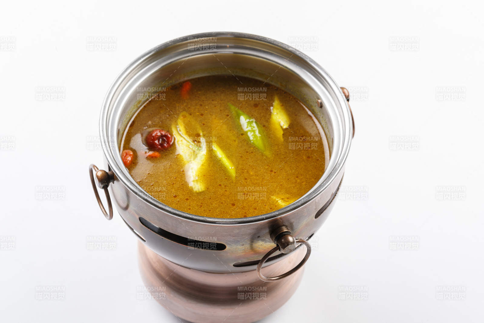 白色背景上的小火锅装的鸡汤锅底图片