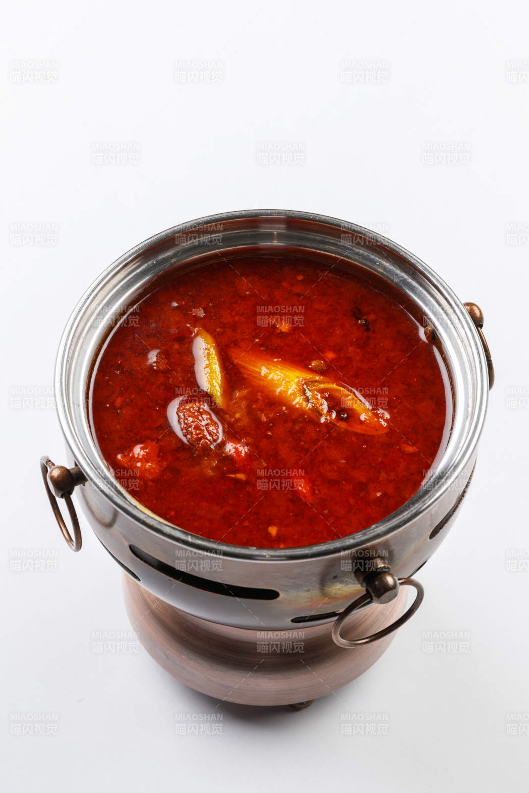 白色背景上的小火锅装的香辣红油锅底图片