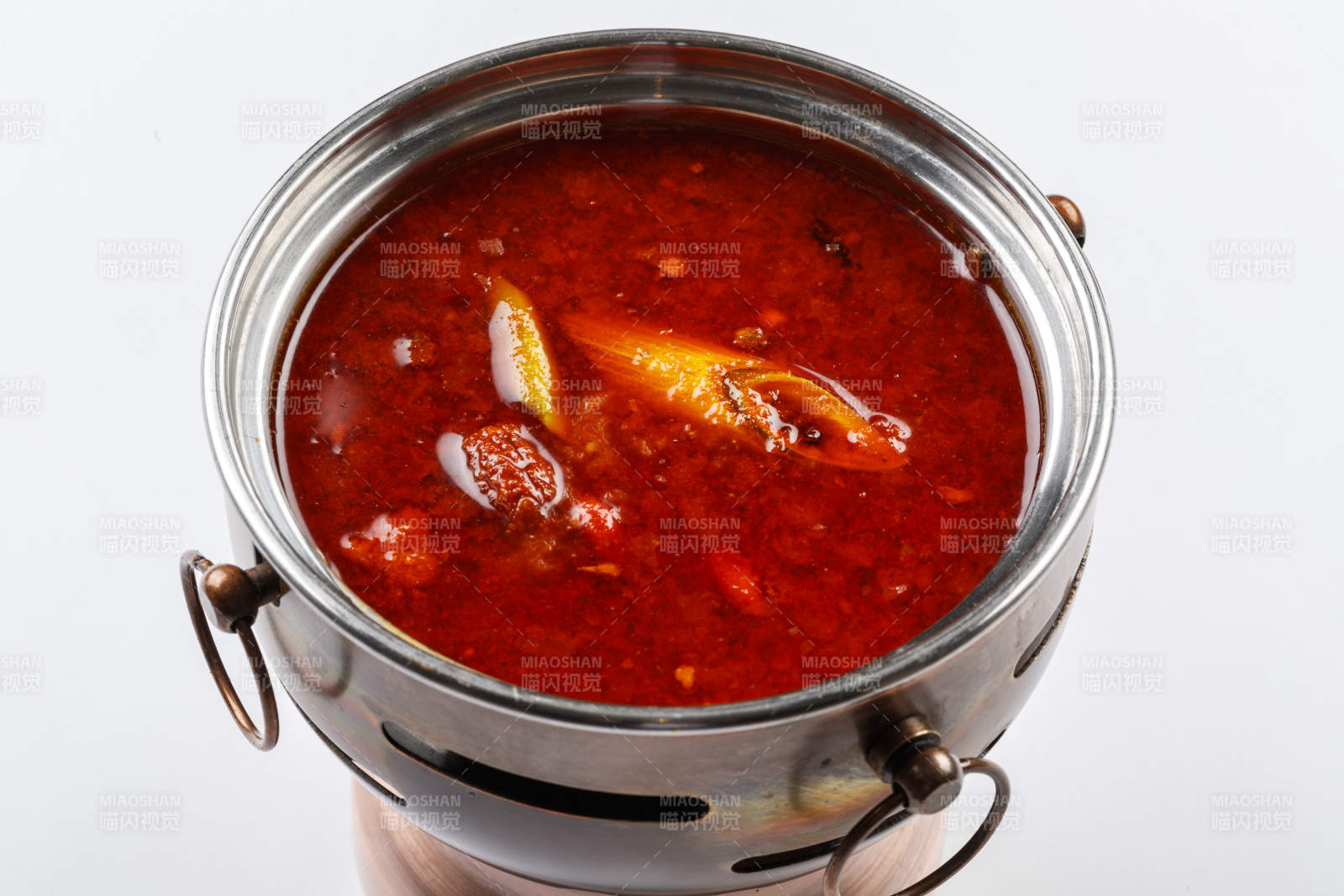 白色背景上的小火锅装的香辣红油锅底图片