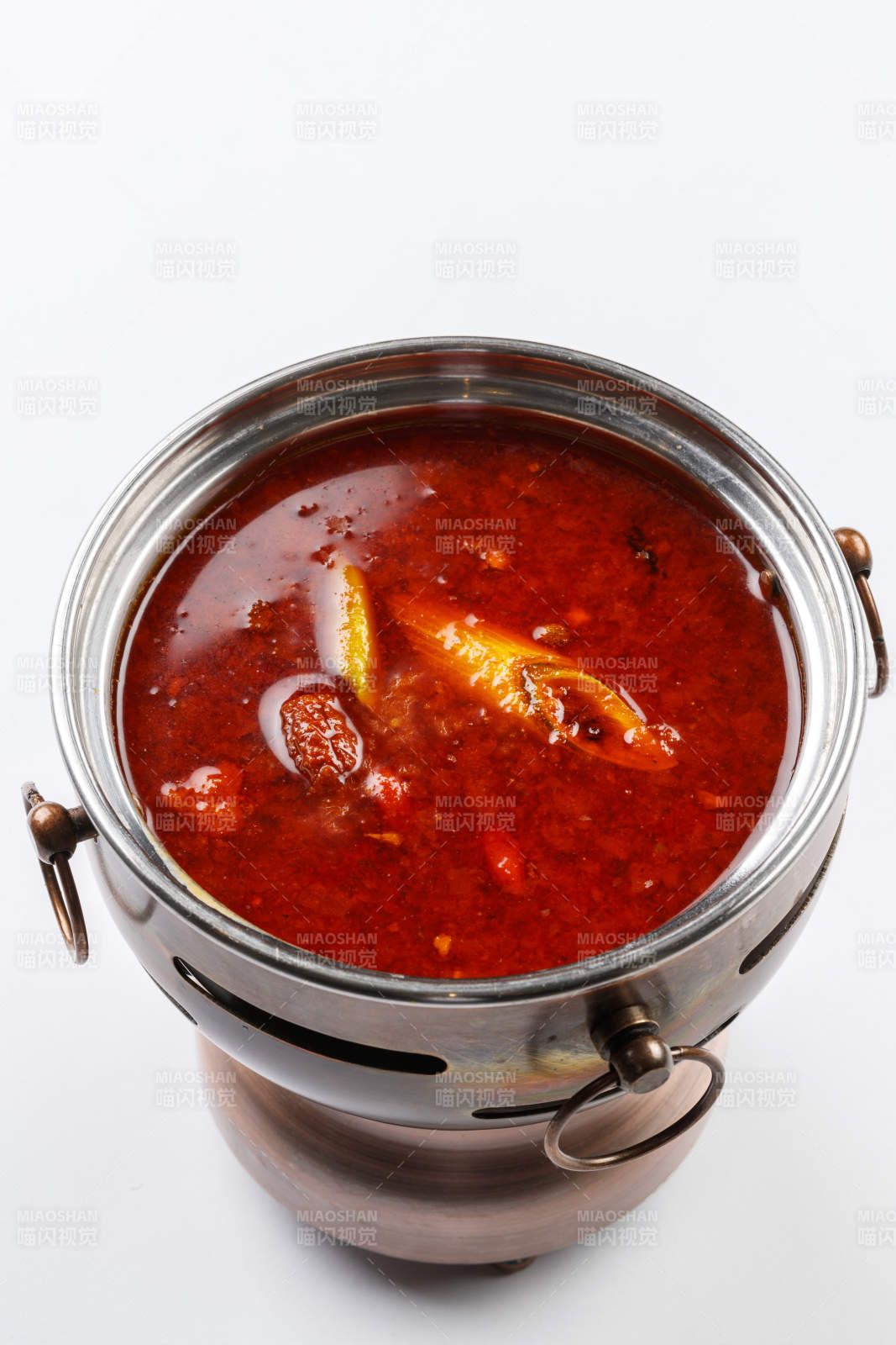 白色背景上的小火锅装的香辣红油锅底图片