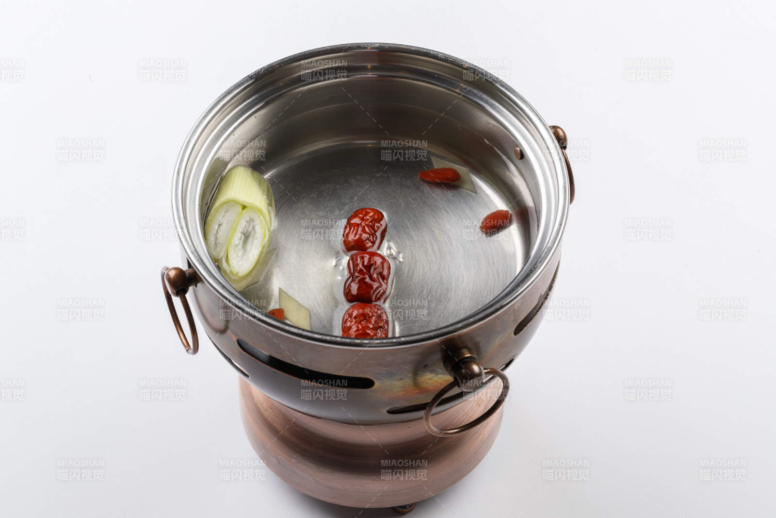 白色背景上的小火锅装的清汤锅底图片