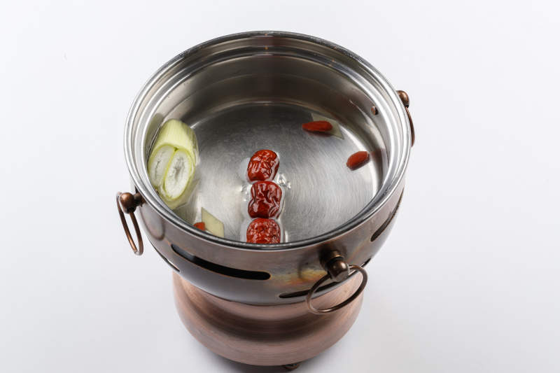 白色背景上的小火锅装的清汤锅底图片