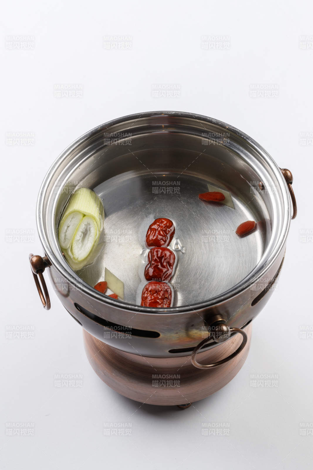 白色背景上的小火锅装的清汤锅底图片