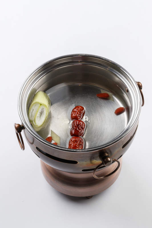 白色背景上的小火锅装的清汤锅底图片