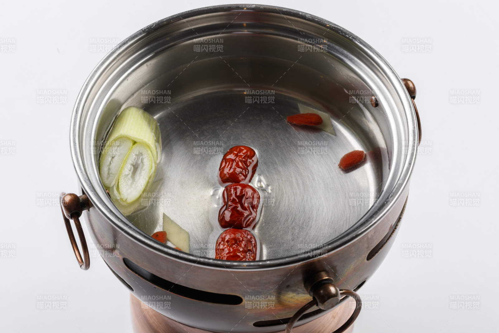 白色背景上的小火锅装的清汤锅底图片