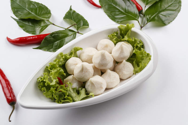 白色背景上的长瓷盘装的涮肉食材手打鱼丸图片