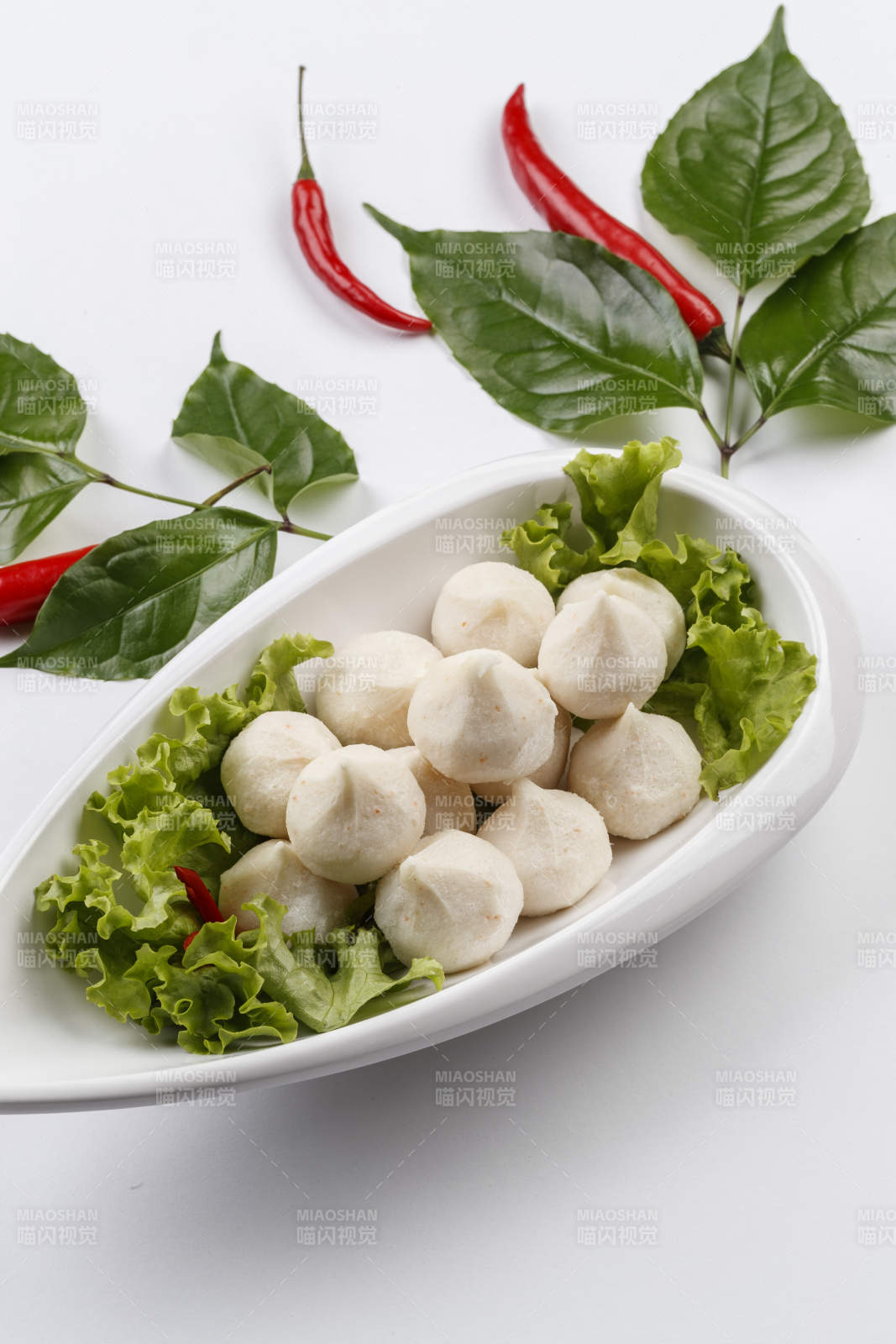 白色背景上的长瓷盘装的涮肉食材手打鱼丸图片