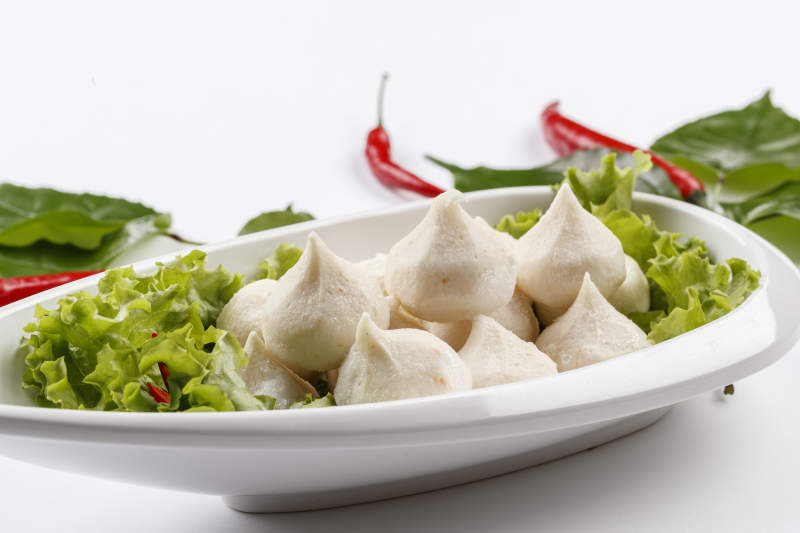 白色背景上的长瓷盘装的涮肉食材手打鱼丸图片