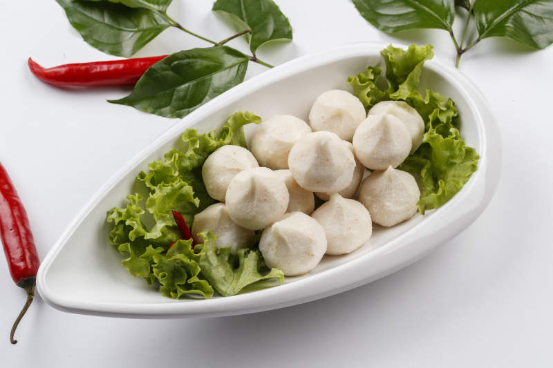 白色背景上的长瓷盘装的涮肉食材手打鱼丸图片